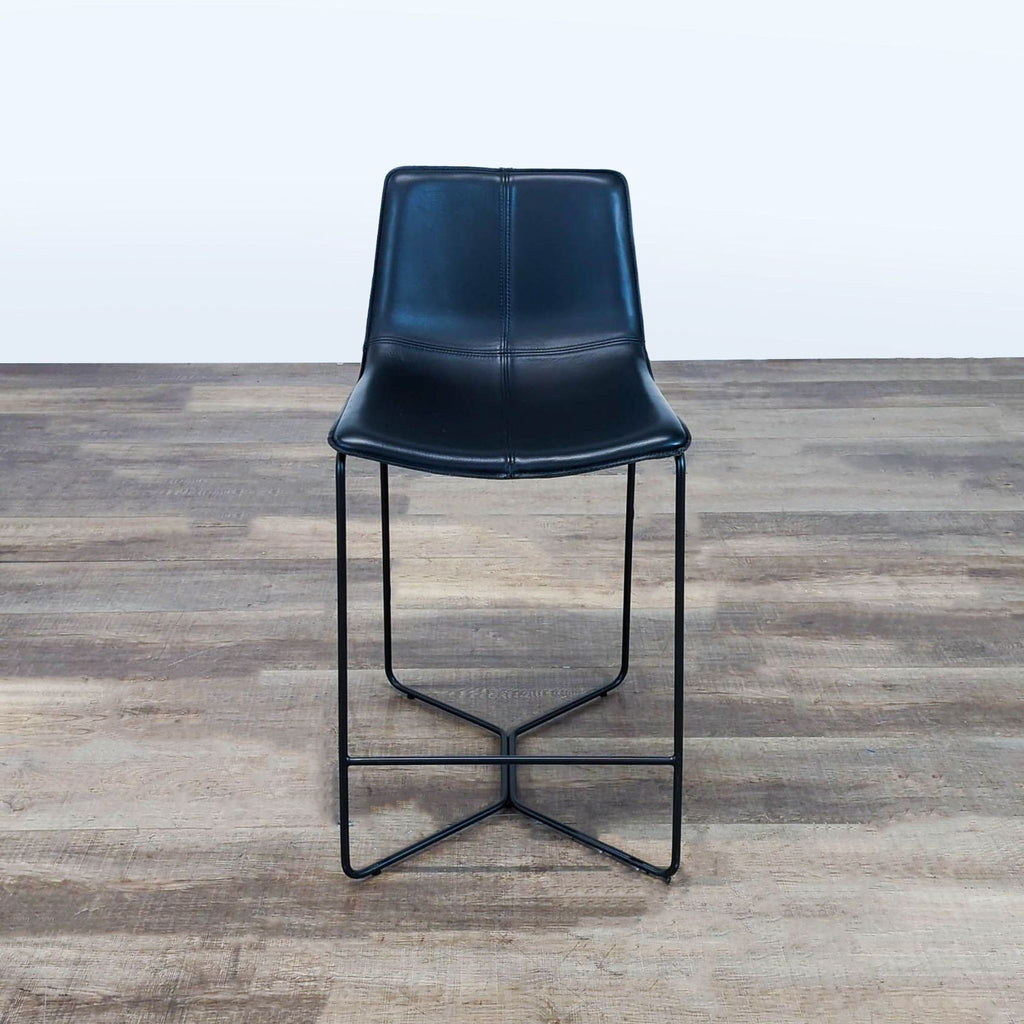 1. Front view of a modern black bar stool with a contoured seat and slim metal legs, from West Elm.