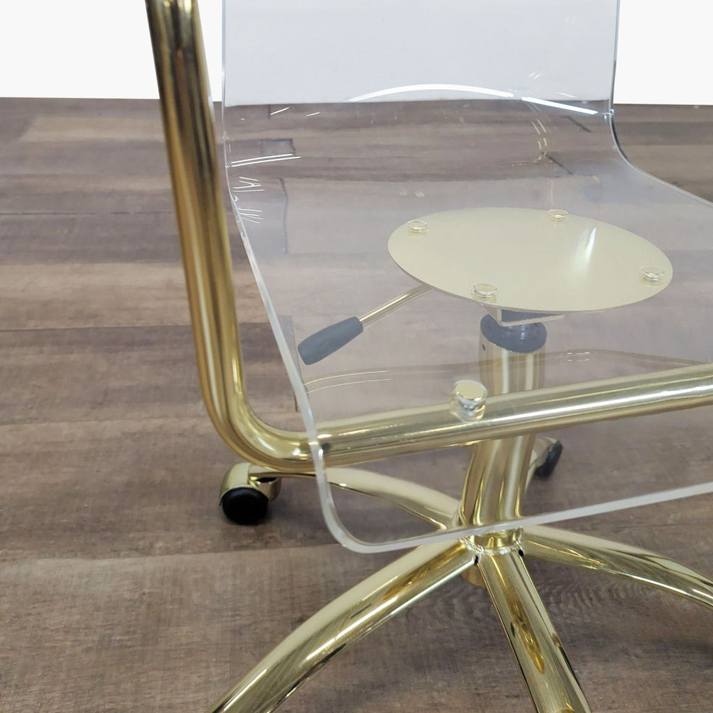 3. Close-up of Pottery Barn acrylic chair, showing gold hydraulic base, lever, and detail of the seat on rolling casters.