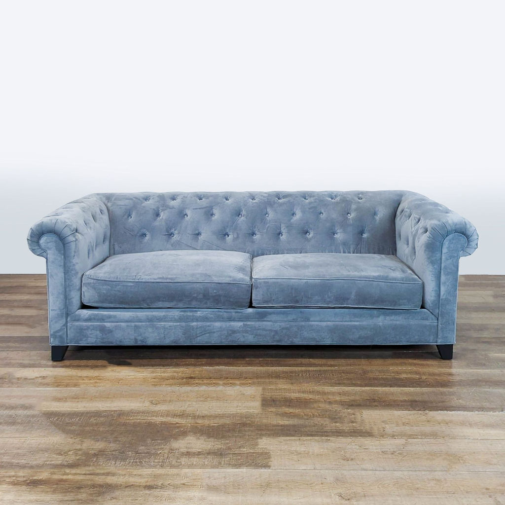 Macy's light blue velvet sofa with tufted backrest and rolled arms, designed for three people.