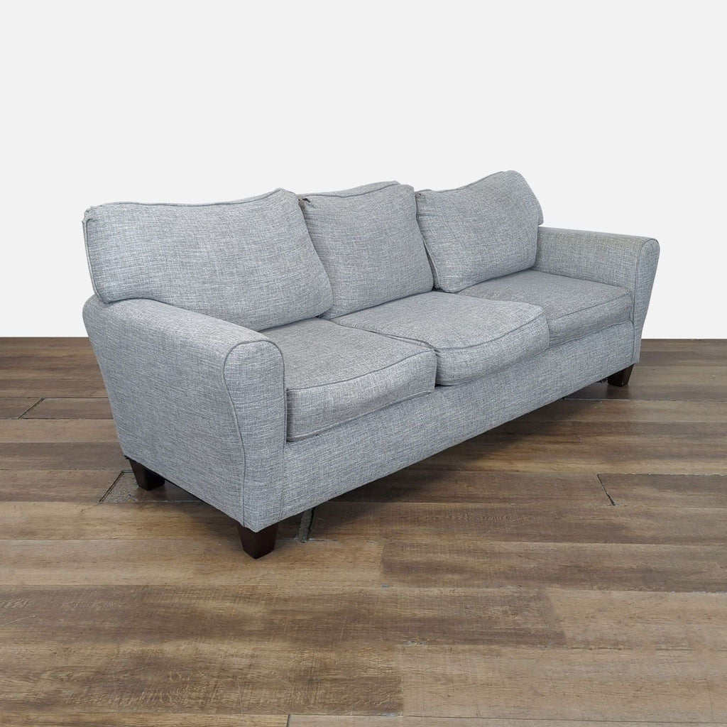 2. Angled side view of Wayfair 3-seat sofa in textured light gray fabric with classic rolled arms and short legs.