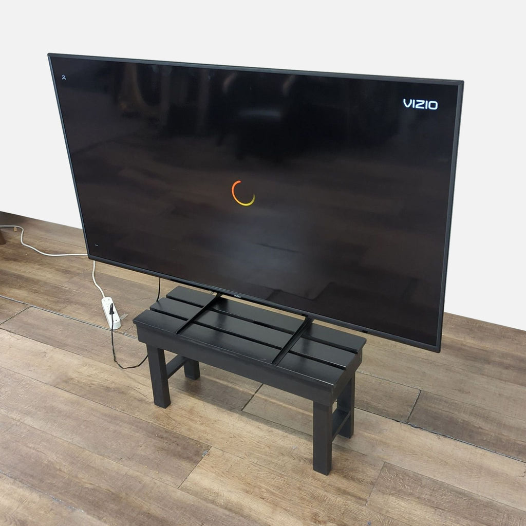 Angled view of a sleek 70-inch Reperch flat screen TV on a sturdy bench, showing its slim, modern design.