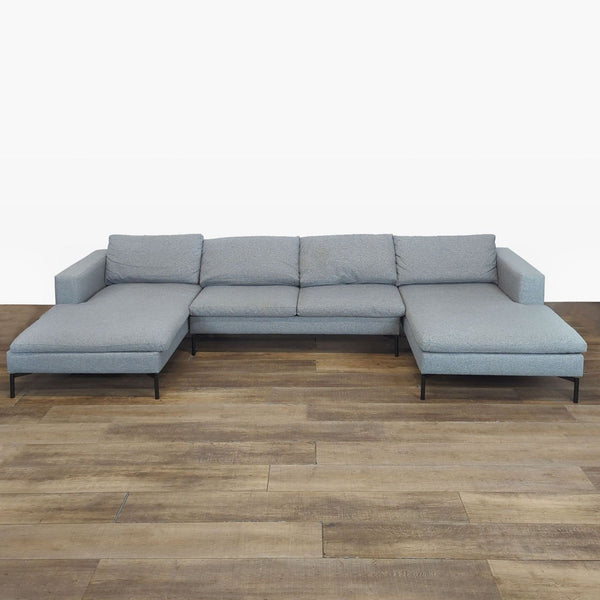 Modern Blu Dot sectional with wide arms, plush loose cushions, and angular powder-coated steel legs.