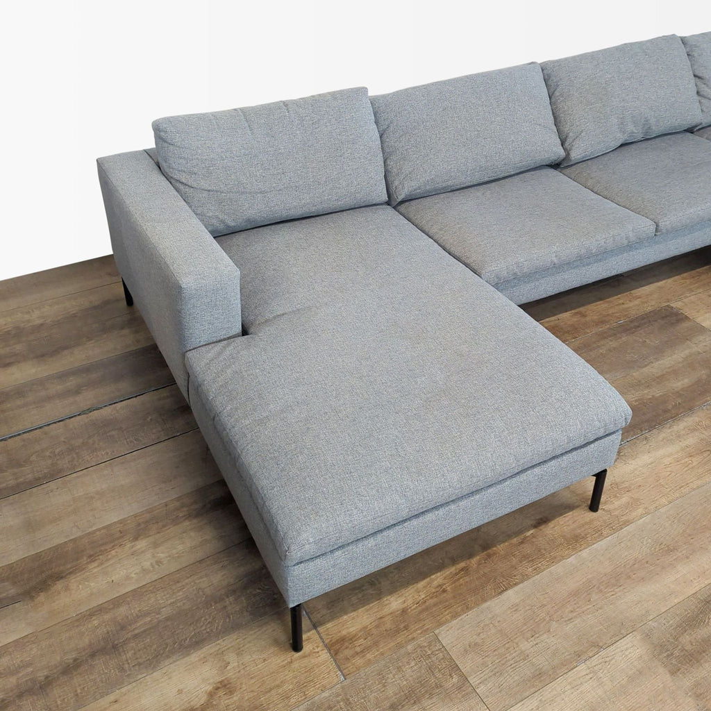 2. Close-up of Blu Dot sectional showing soft cushions, wide armrest, and steel legs on wood floor.  