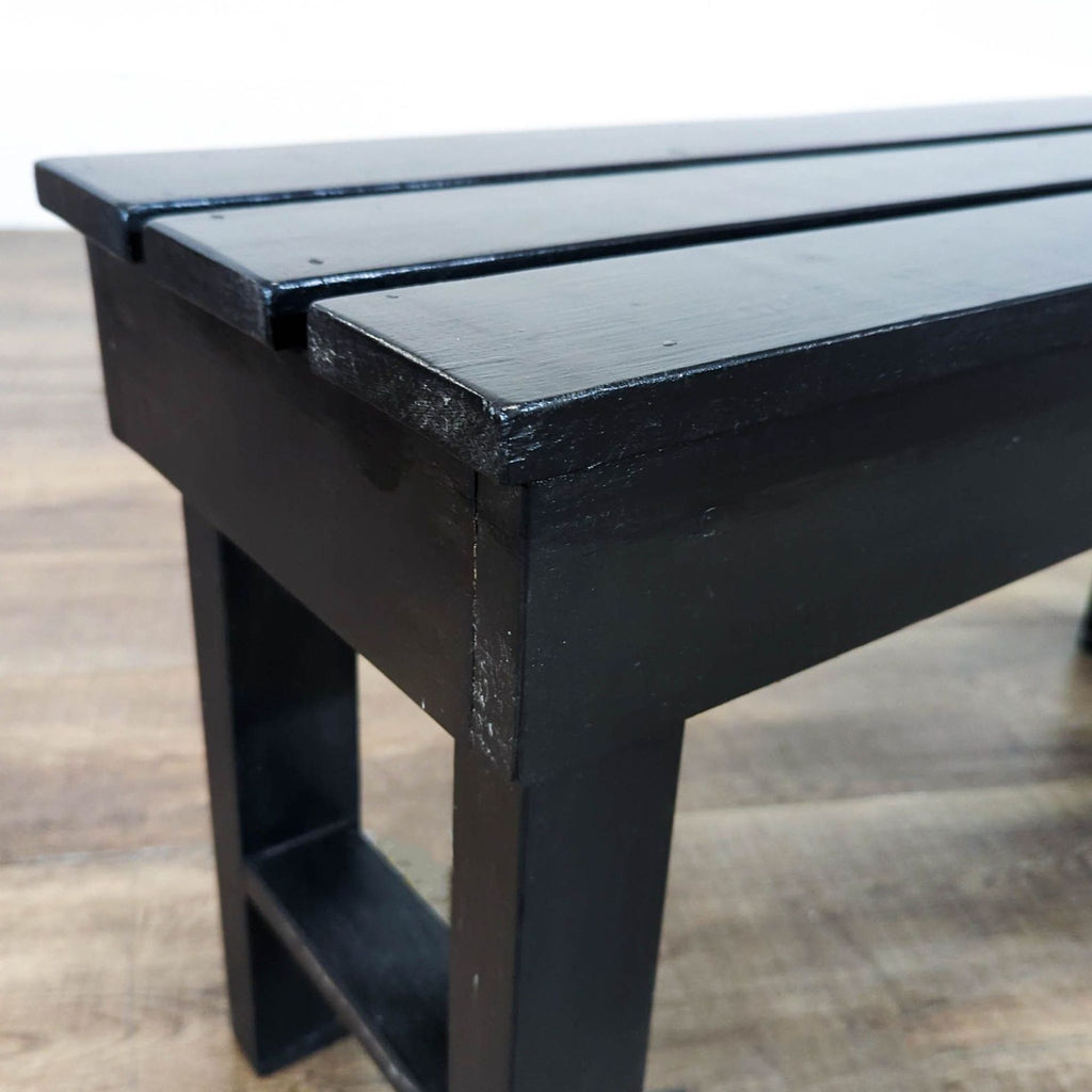 3. Close-up of Reperch slatted black bench corner, highlighting smooth finish and build, on wood flooring.