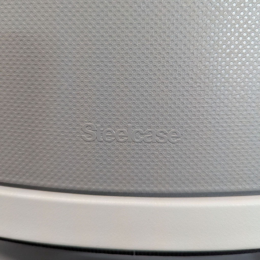 3. Close-up of the Steelcase brand logo embossed on the chair’s textured gray back panel.