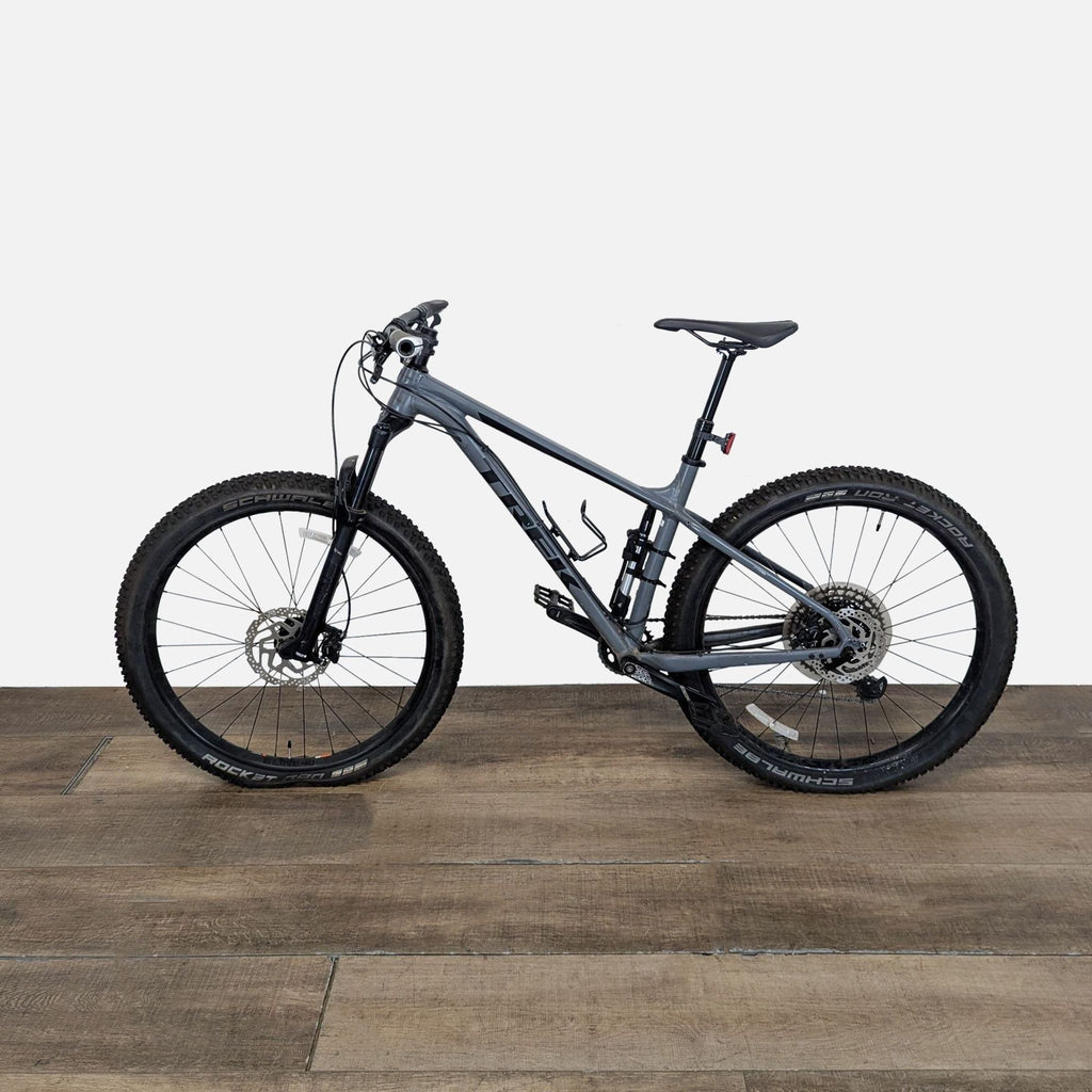 2. Side view of a Trek mountain bike featuring wide Schwalbe Rocket Ron tires and dual suspension, in good condition.