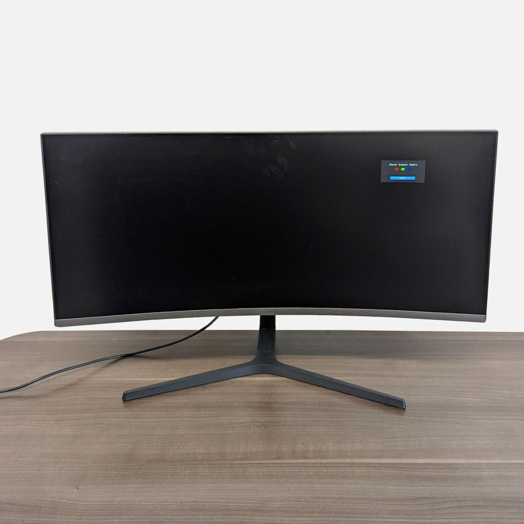 Front view of a Samsung UltraWide curved monitor on a desk, showing a clean screen and modern stand.