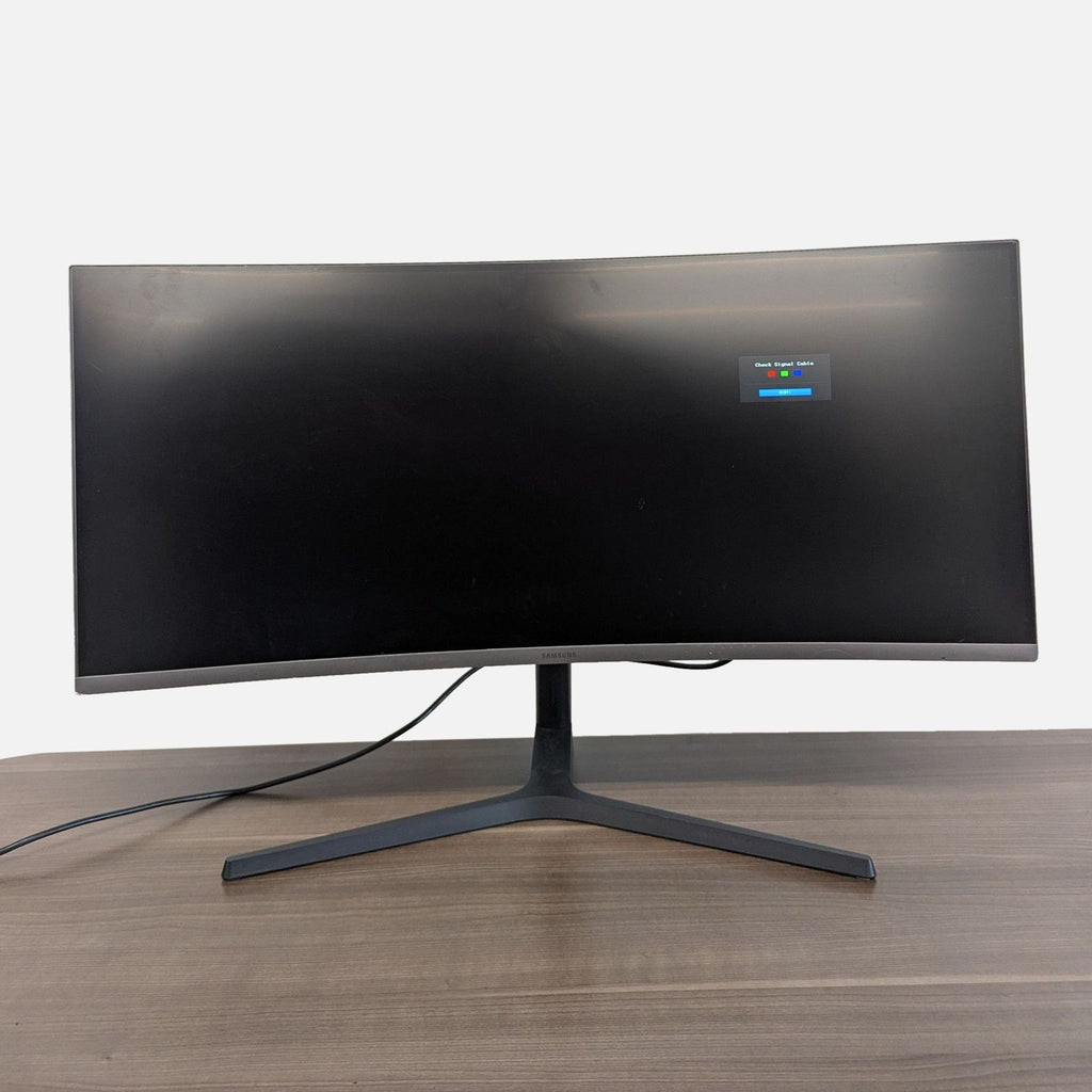 Front angle of a Samsung curved monitor with a wide display and sturdy stand, power cable connected.