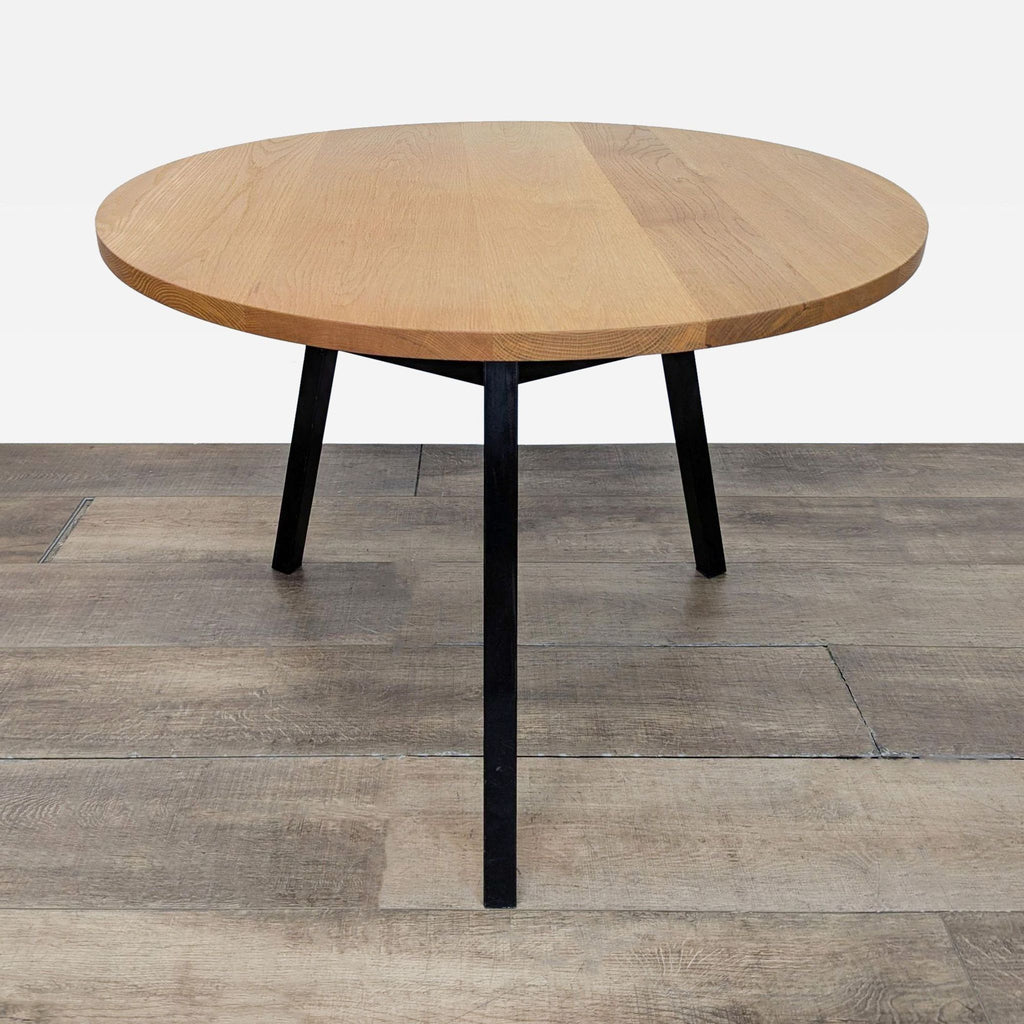 3. Modern round dining table with oak surface and black steel base, made by OHIO Furniture.