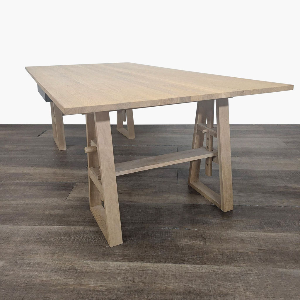 1. Industry West desk with solid wood construction and an adjustable trestle base, shown on wood flooring.  