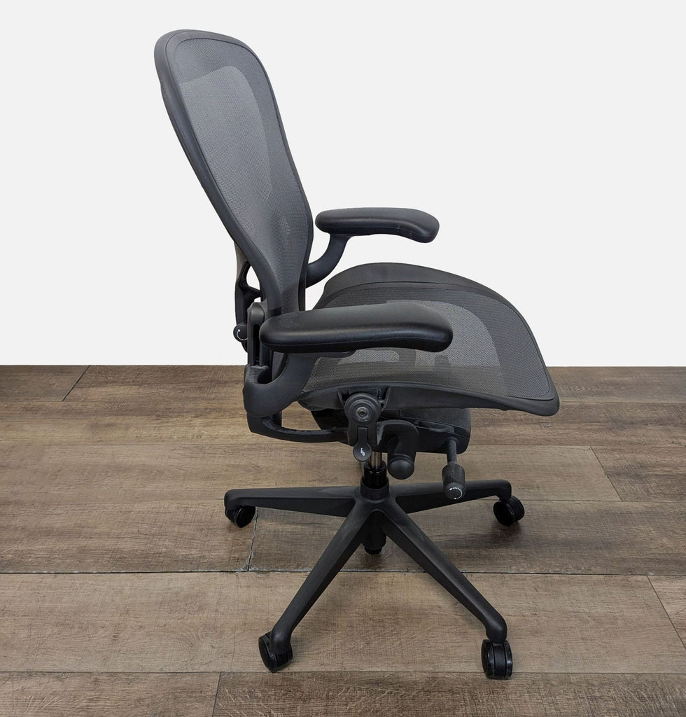 2. Side view of a Herman Miller office chair showing contoured seat, mesh backrest, and adjustable armrests on castor wheels.