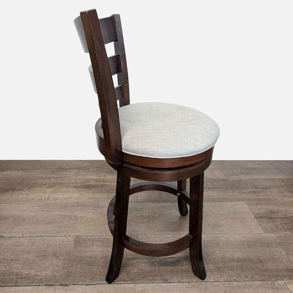 3. Side view of a Reperch stool with a curved wooden back and a padded, light-colored round seat.