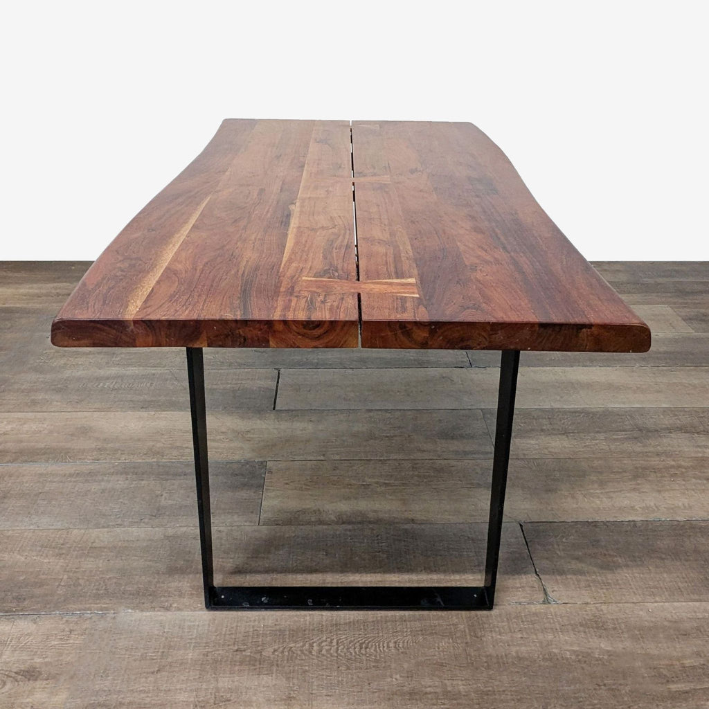 Front view of Crate and Barrel acacia dining table, featuring live-edge wood top and black steel legs.