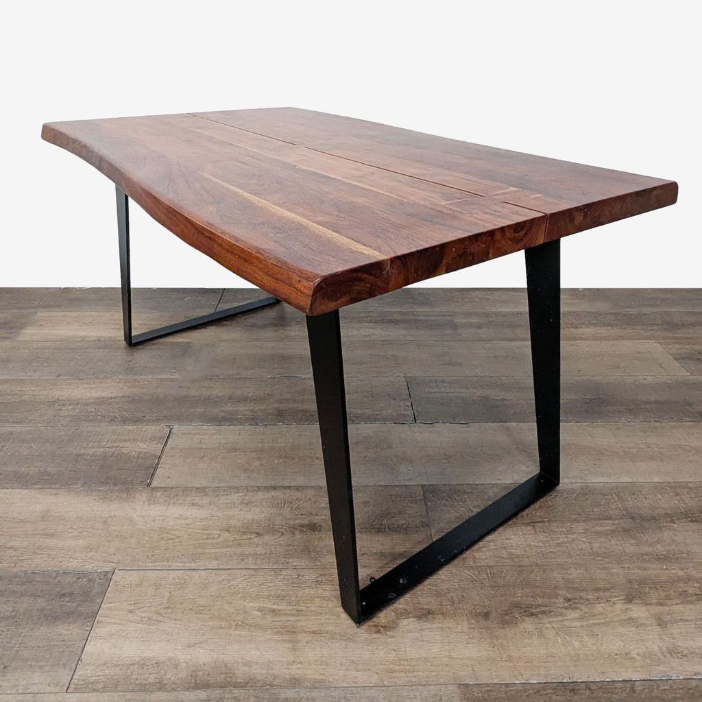Live-edge acacia dining table with butterfly joints and matte black U-shaped steel legs on wood floor.