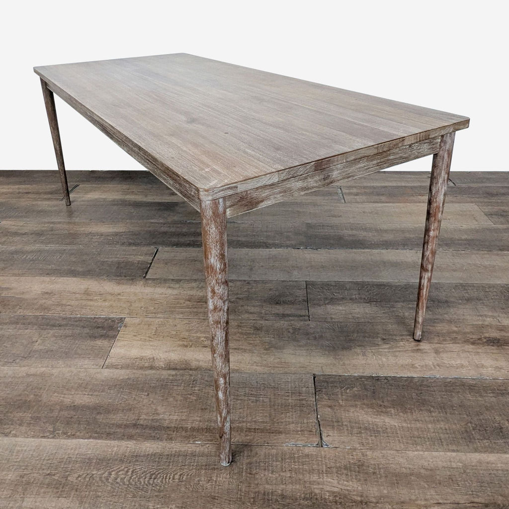 3. Angled view of a West Elm wooden dining table featuring tapered legs and a rustic, natural finish.