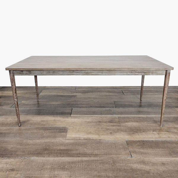1. Rectangular West Elm dining table with a rustic wood finish and slim tapered legs, shown on a wooden floor.