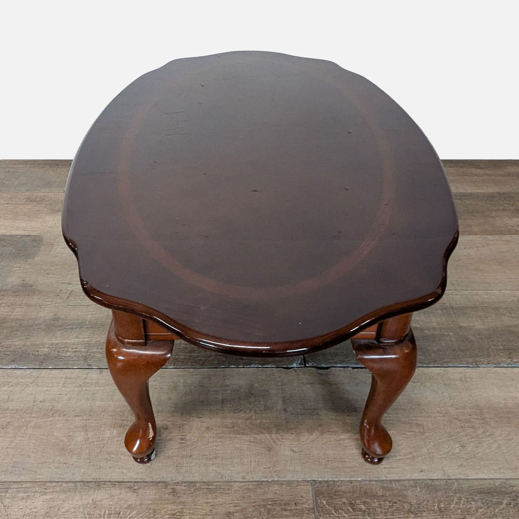 2. Top view of the Reperch coffee table showing its oval shape and scalloped edges on a wood surface.