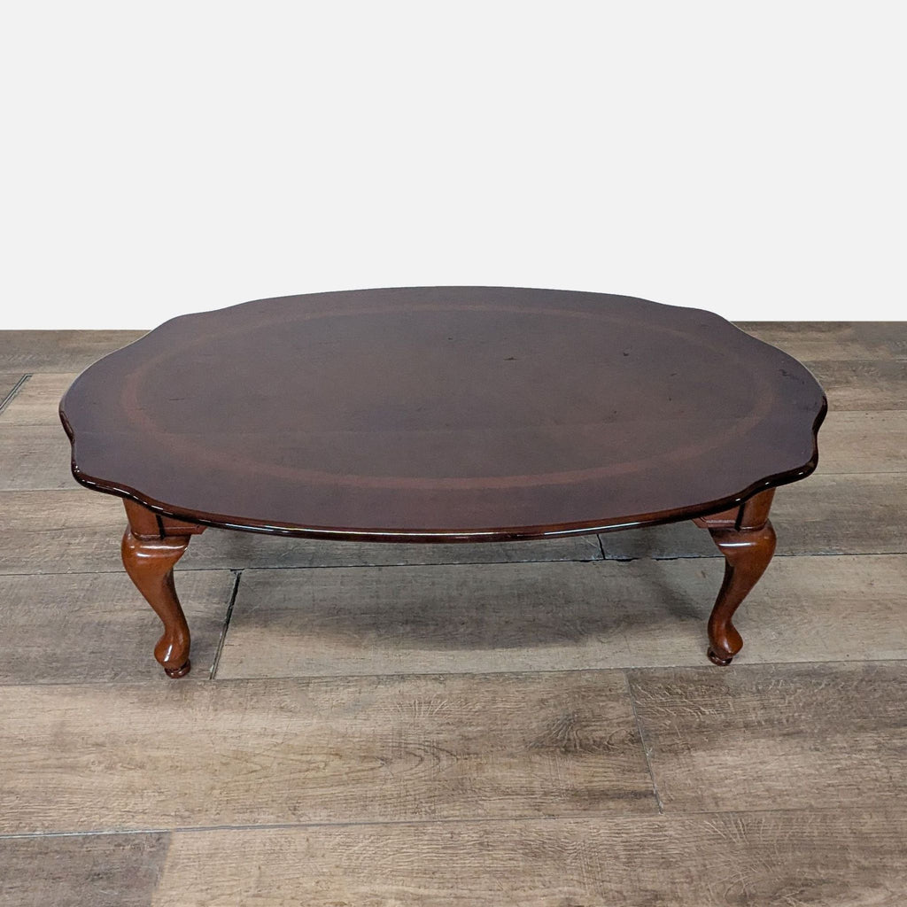 1. Oval dark wood Reperch coffee table with curved edges and cabriole legs displayed on a wooden floor.
