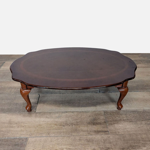 1. Oval dark wood Reperch coffee table with curved edges and cabriole legs displayed on a wooden floor.