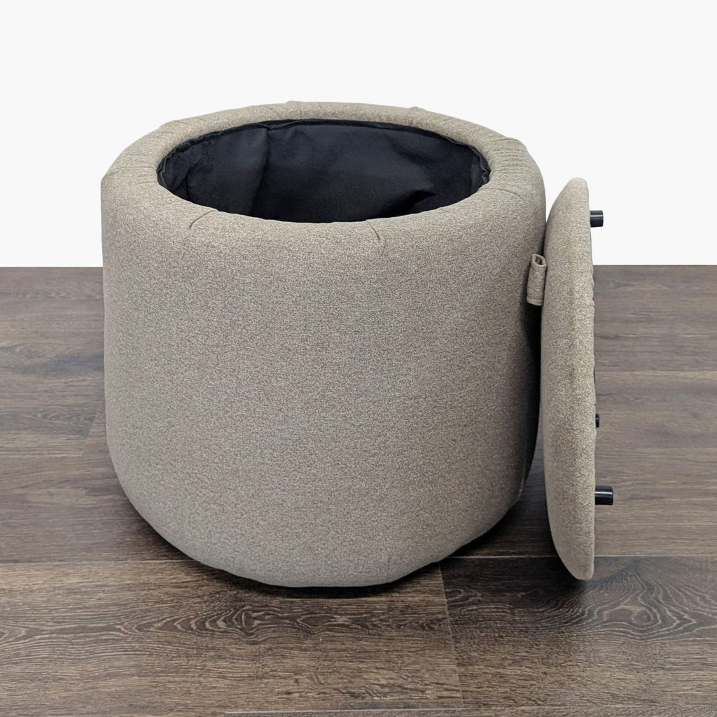 2. Ikea round beige ottoman with removable lid, revealing spacious interior for storage, on wood floor.  