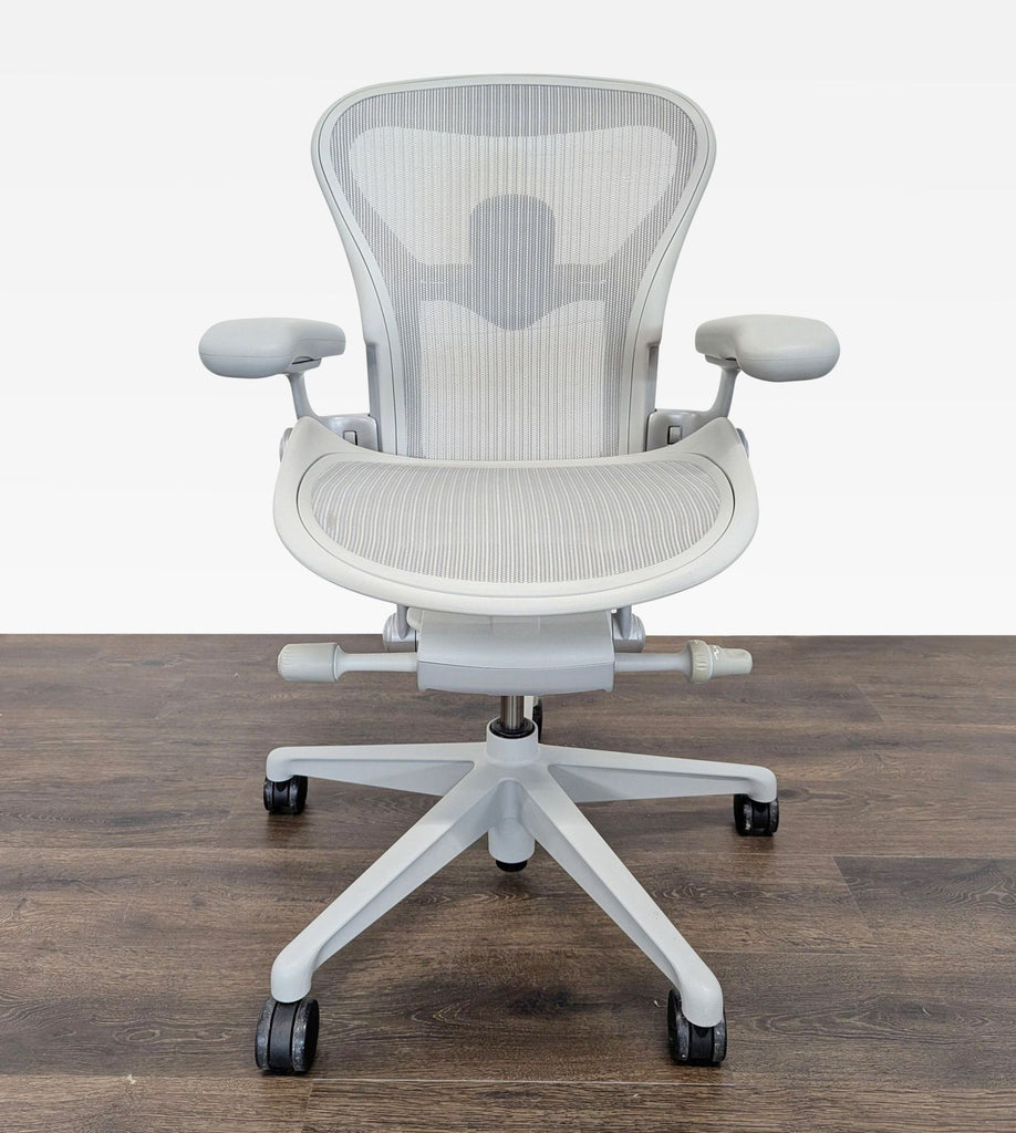 1. Front view of a Herman Miller ergonomic office chair with breathable mesh and adjustable lumbar support on wood floor.  