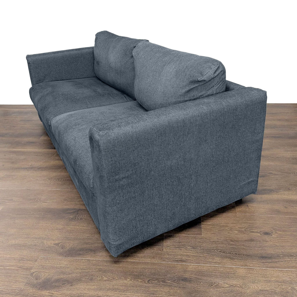 2. Angled side view of an Ikea sleeper sofa in dark gray fabric, showing thick seat and back cushions.