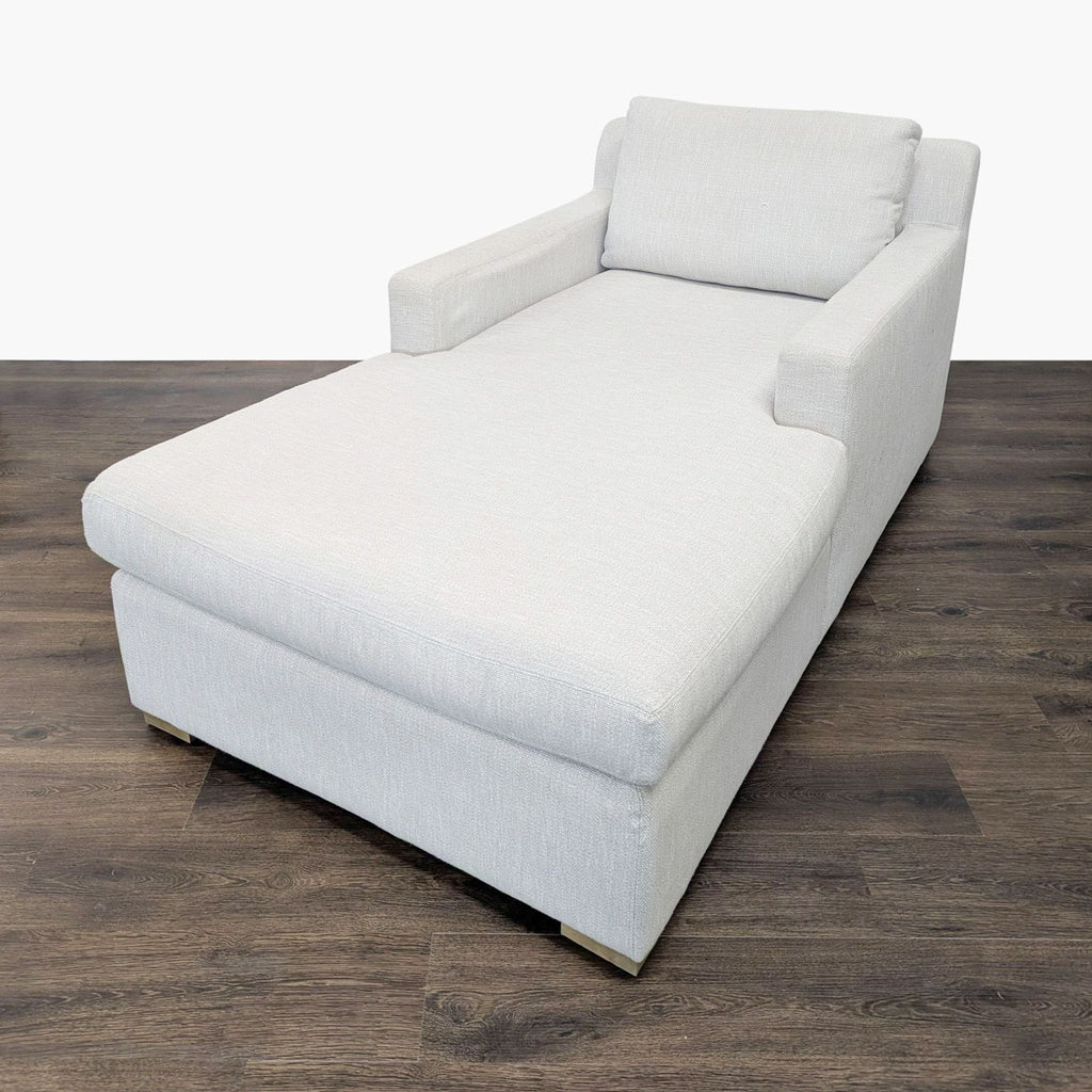 3. Angled side view of a Restoration Hardware lounge chaise in light gray fabric on a dark wooden floor.