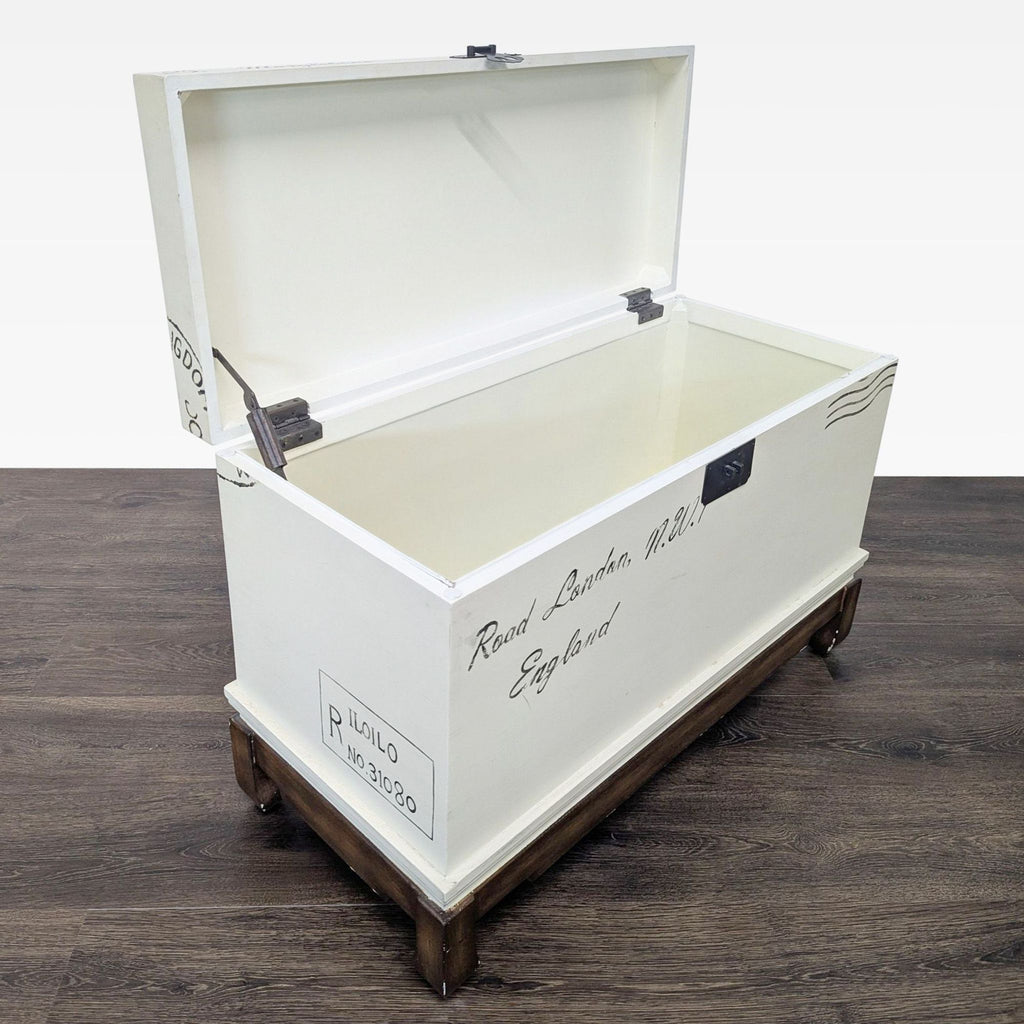 2. Open Reperch trunk in cream finish, revealing spacious interior, accented by hand-painted postage marks.  