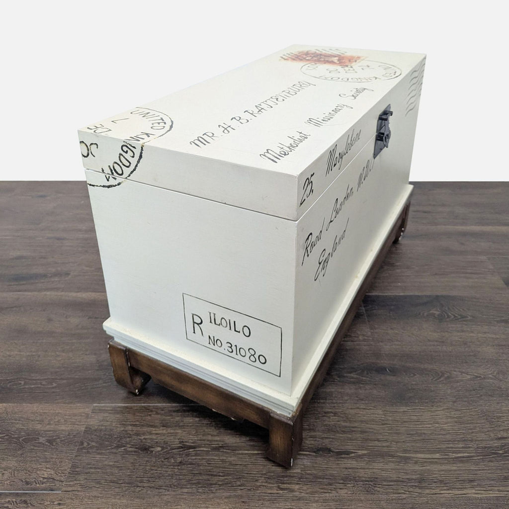 3. Reperch antiqued cream trunk with postal-themed hand-painted details and wooden base, angled side view.