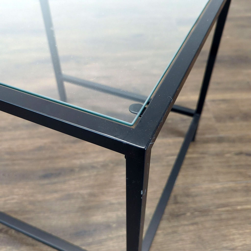 2. Close-up of Reperch side table corner showing black metal frame and clear glass top detail.