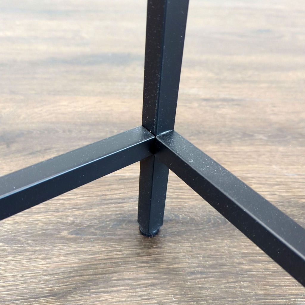3. Detailed view of black metal leg connection on Reperch side or console table against wood floor.