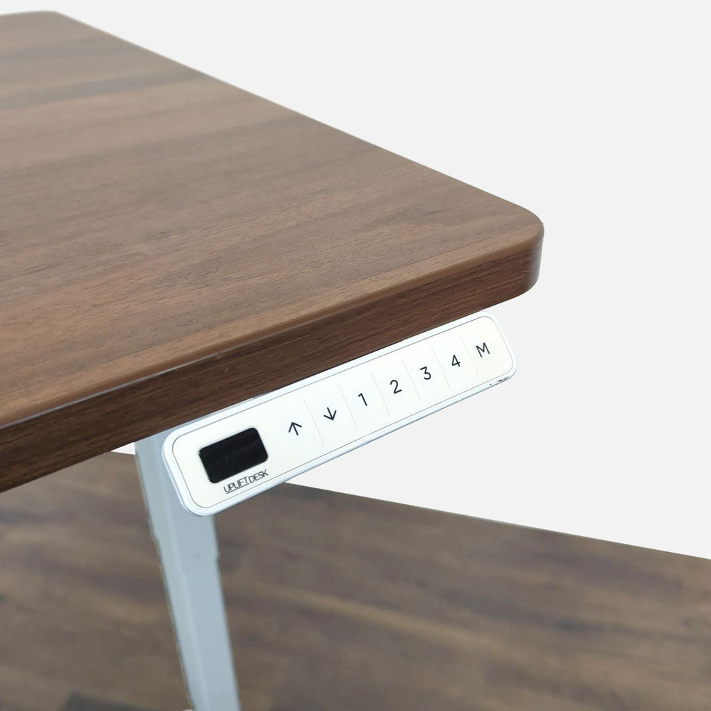 1. Close-up of a UPLIFT desk’s control panel with programmable height adjustment buttons under a wood tabletop.