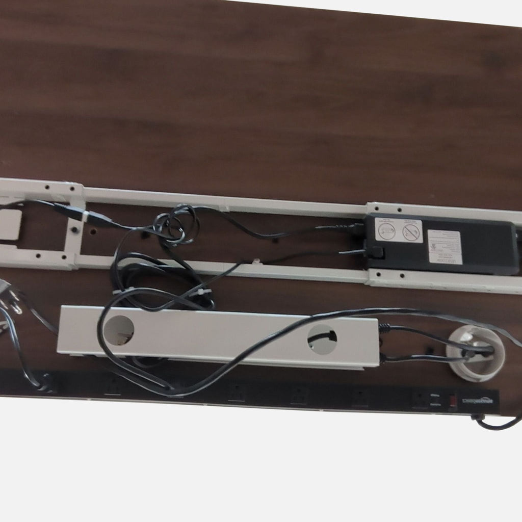 2. Underside view of a UPLIFT desk showing cable management, power supply, and power strip mounted on wood.