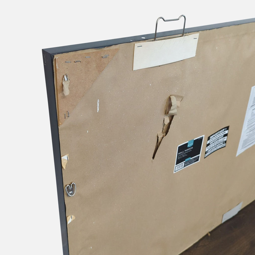 Angled rear view of Target Home mirror highlighting hanging hardware and damaged brown backing paper.