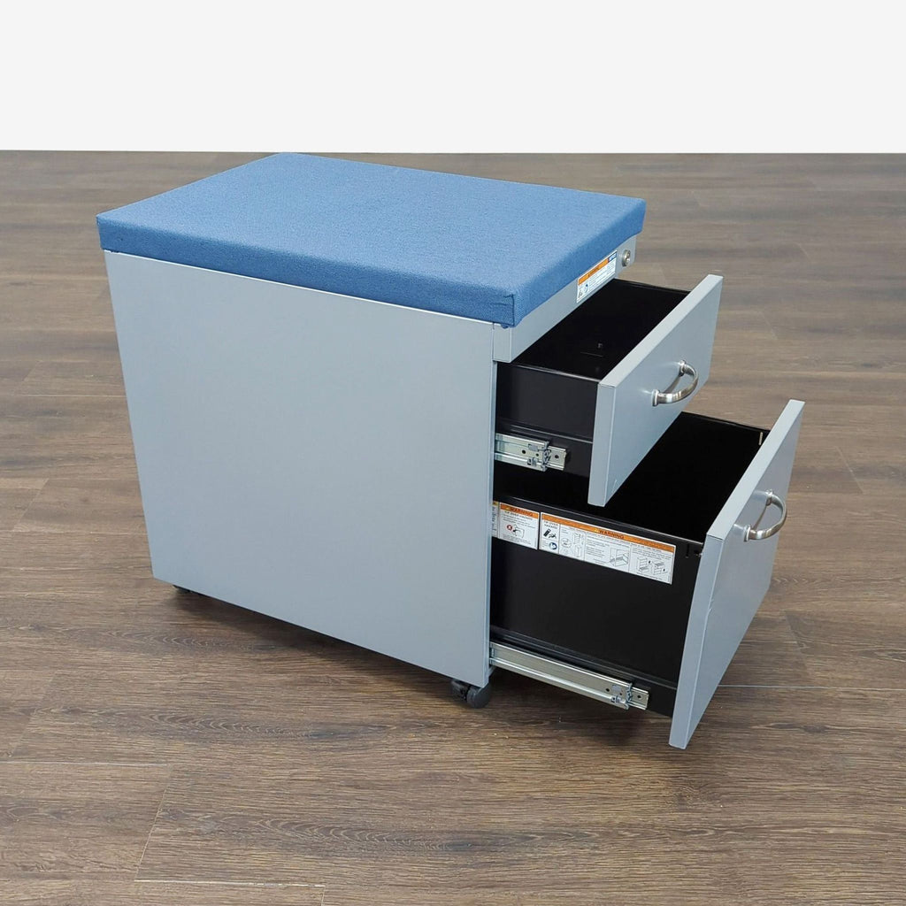 3. Reperch two-drawer cabinet with a blue cushioned top, both drawers open, placed on a brown wood floor.