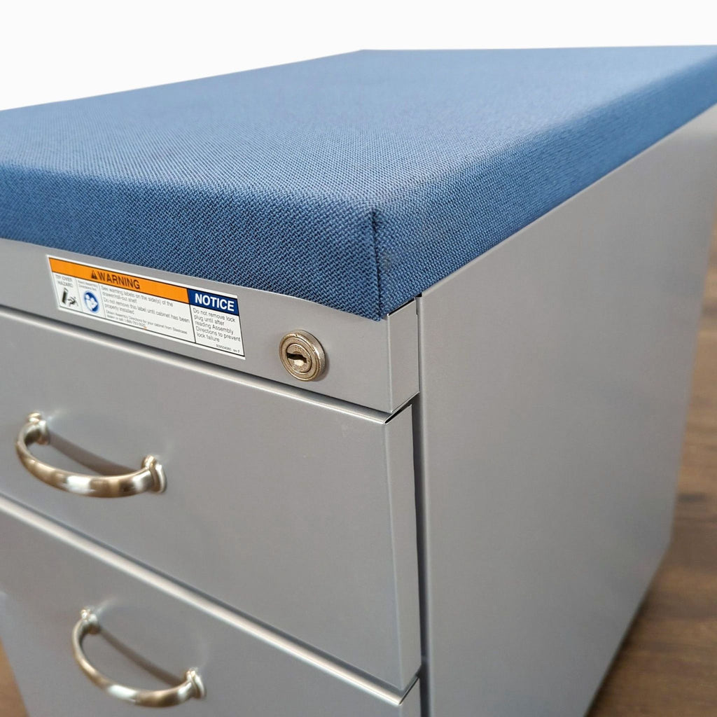 2. Top view of a Reperch cabinet, highlighting blue cushioned seat, metal handles, and lock above top drawer.