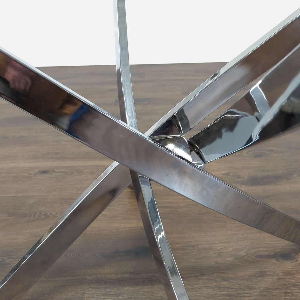 1. Close-up of intersecting chrome metal legs, part of a Reperch dining set on a wooden floor.