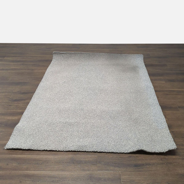 1. Room & Board wool rug with a textured beige surface, shown on a dark wood floor.
