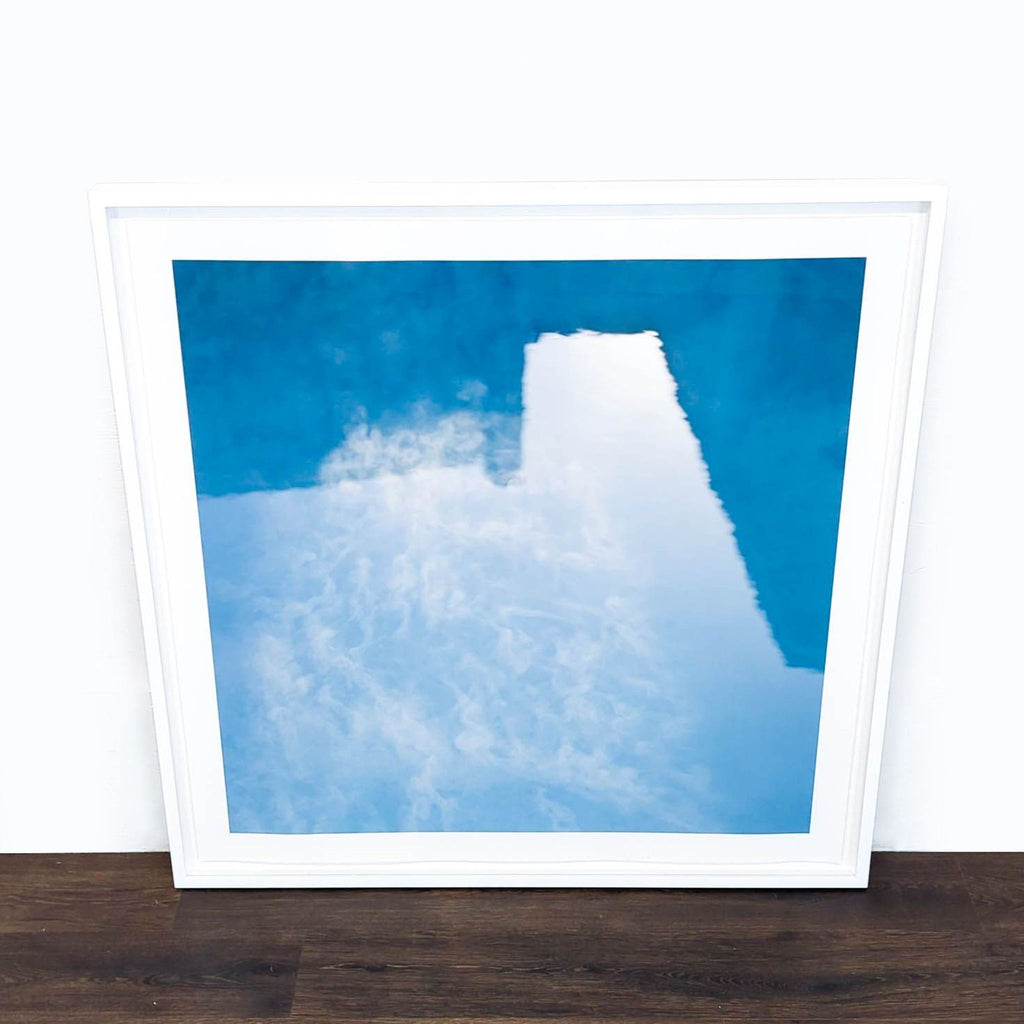 1. Framed abstract print by Reperch with blue and white tones, leaning against a white wall on wood floor.