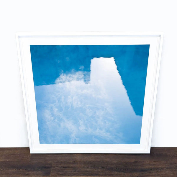 1. Framed abstract print by Reperch with blue and white tones, leaning against a white wall on wood floor.