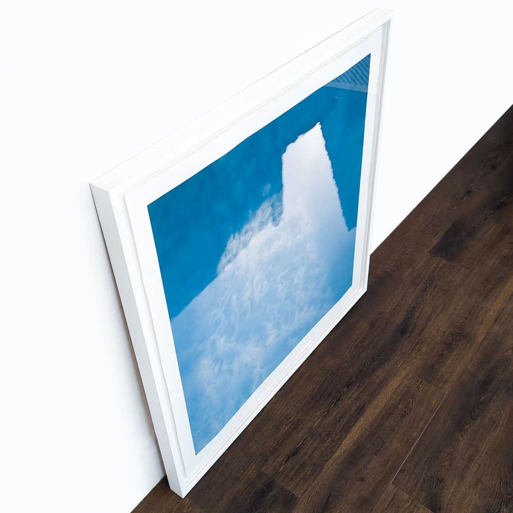 3. Angled overhead view of Reperch framed print featuring an abstract sky and blue reflection in white frame.