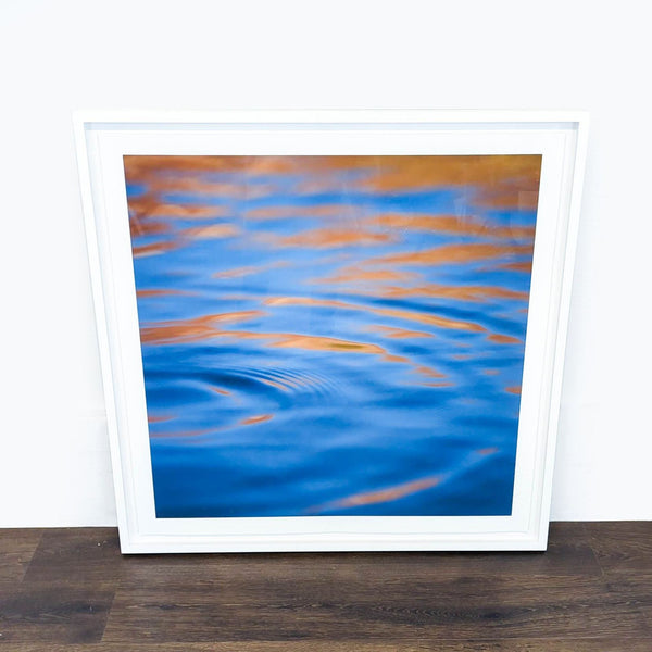 1. Framed print by Reperch showing abstract blue and orange water ripples, leaning against a white wall.