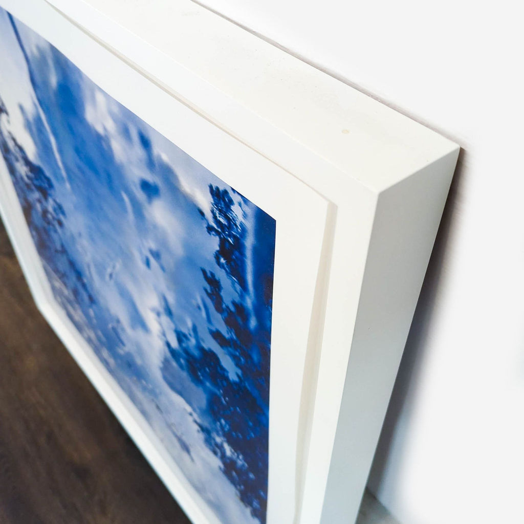 3. Close-up of a Reperch print’s white frame corner, highlighting the vivid blue reflective artwork inside.