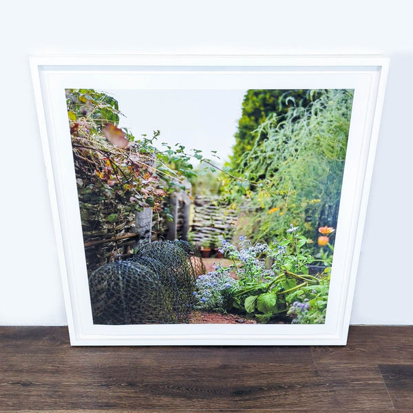 1. Framed Reperch print featuring a garden scene with lush greenery, flowers, and rustic woven fencing.
