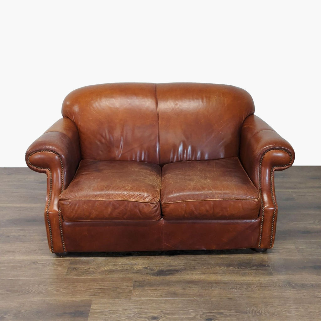 2. Front view of a brown leather Robinson & Robinson loveseat with rolled arms and nailhead trim.