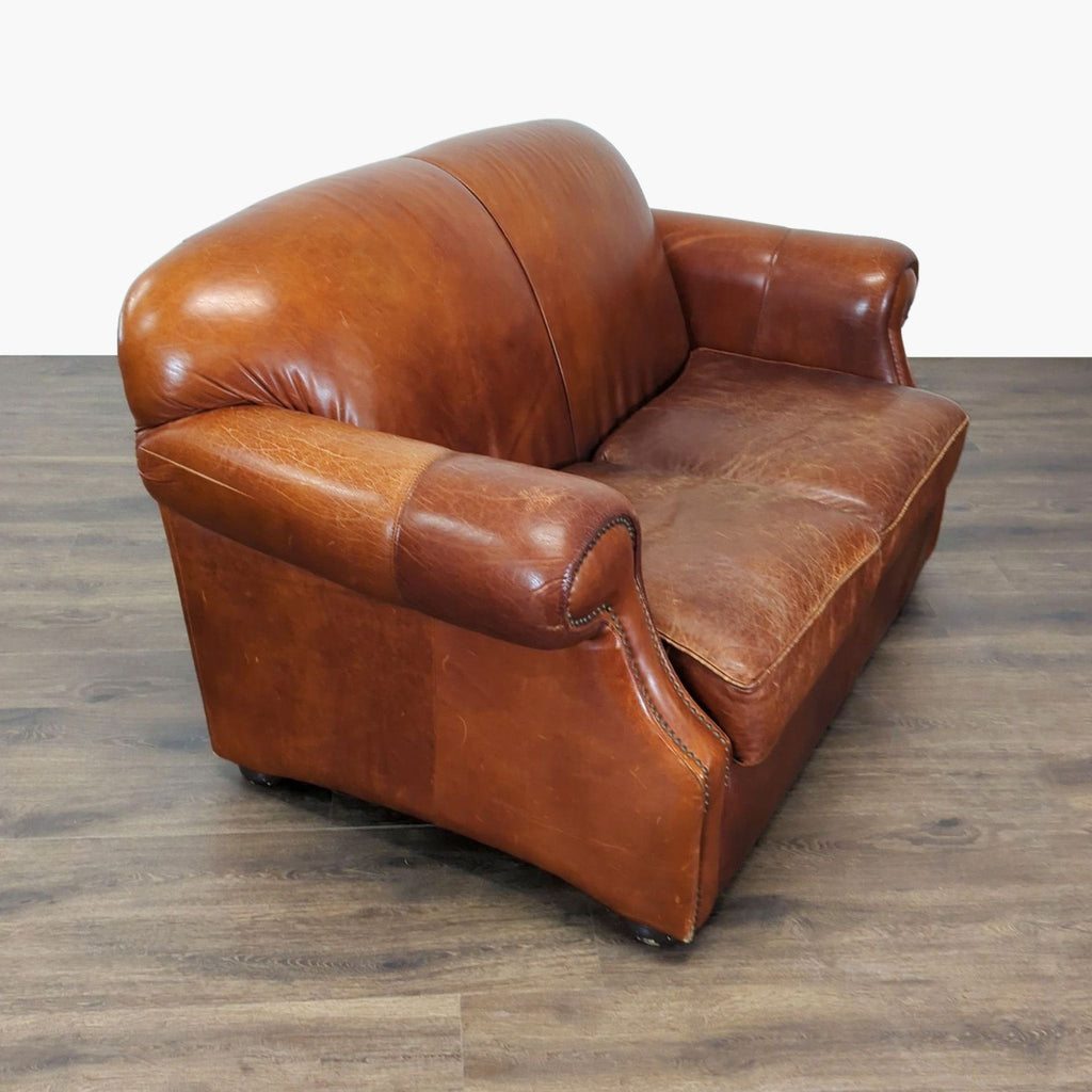 3. Angled side view of a vintage brown leather Robinson & Robinson loveseat with curved arms and seat cushions.