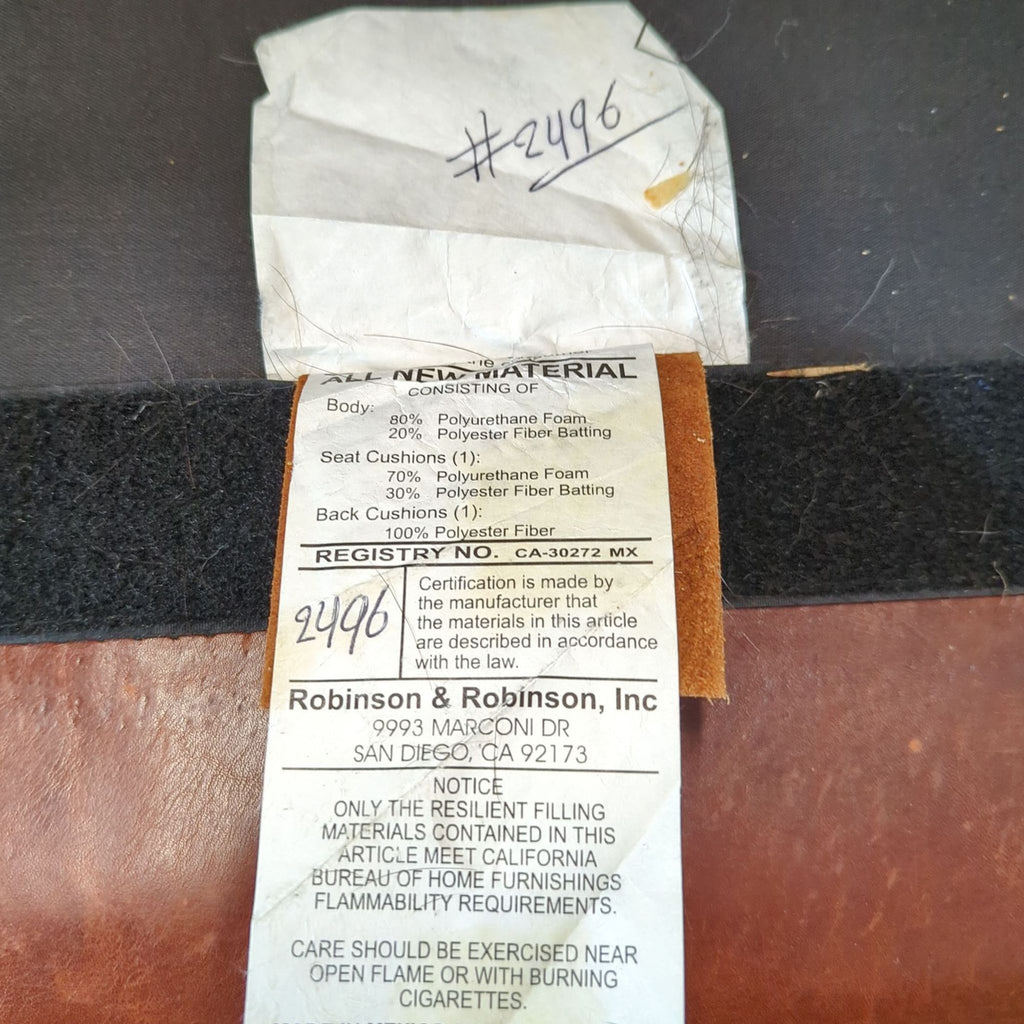 1. Close-up of the Robinson & Robinson loveseat material tag showing foam and fiber content and safety notice.