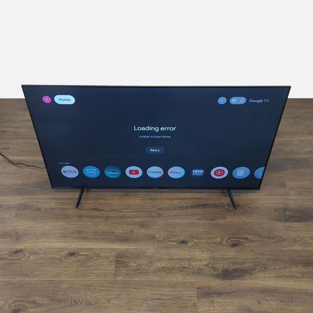 2. TCL smart TV on a wooden floor showing Google TV loading error and app icons like Netflix and Disney+.