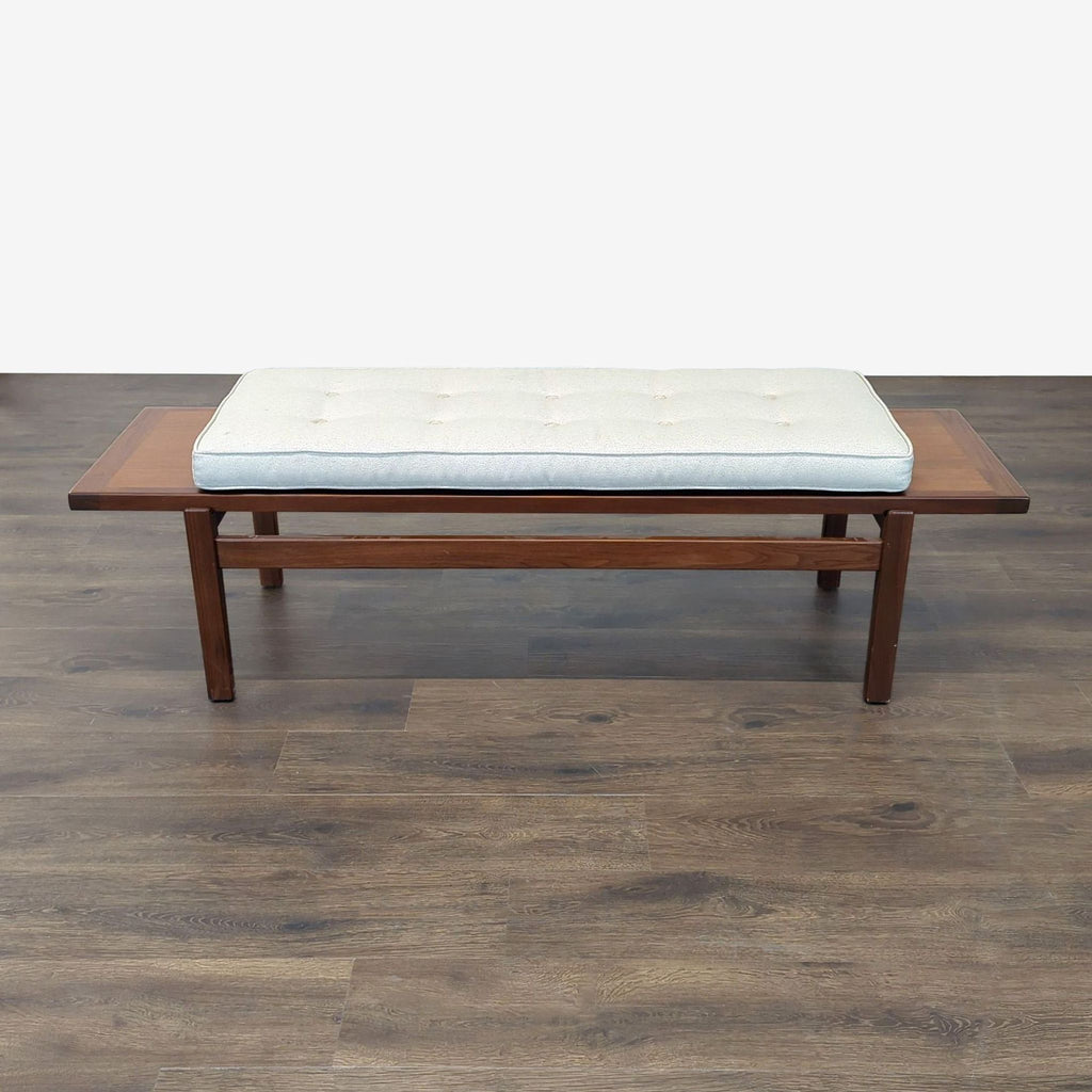 Mid-century modern Reperch bench with wooden frame and white tufted cushion on dark floor.  