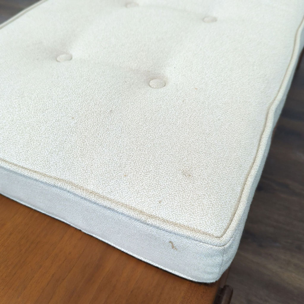 Close-up of the Reperch bench’s white textured cushion with subtle button tufting details.  
